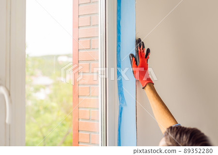 Man in a blue shirt does window installation Man in a blue shirt does window installation 89352280