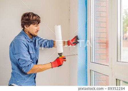 Man in a blue shirt does window installation Man in a blue shirt does window installation 89352284
