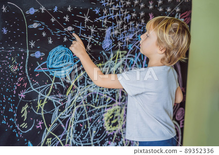 Little boy pointing space, planets and stars on the wall Little boy pointing space, planets and stars on the wall 89352336