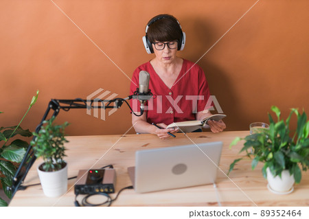 Middle-aged woman radio host making podcast recording for online show - broadcast and dj concept Middle-aged woman radio host making podcast recording for online show - broadcast and dj concept 89352464