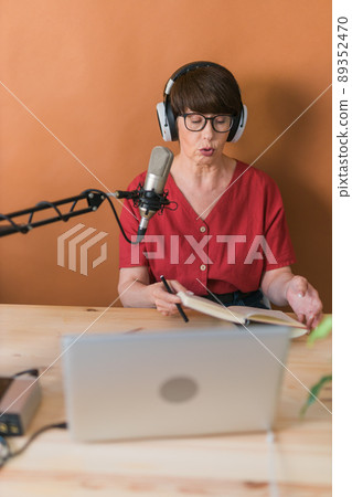 Middle-aged woman radio host making podcast recording for online show - broadcast and dj concept Middle-aged woman radio host making podcast recording for online show - broadcast and dj concept 89352470