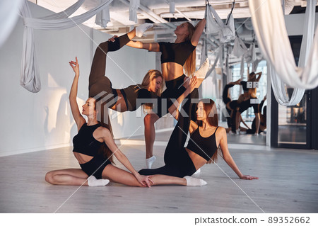 Young women in sportwear help each other stretch before fly yoga training in fitness group 89352662