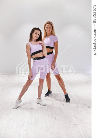 Two beautiful woman posing for camera before dance class in fitness club Two beautiful woman posing for camera before dance class in fitness club 89352675