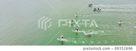 Strong men floating on a SUP boards in a beautiful bay on a sunny day. Aerial view of the men crosses the bay using the paddleboard. Water sports, competitions BANNER, LONG FORMAT Strong men floating on a SUP boards in a beautiful bay on a sunny day. Aerial view of the men crosses the bay using the paddleboard. Water sports, competitions BANNER, LONG FORMAT 89352696
