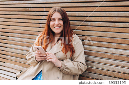 Happy cheerful young woman siting on bench and using smart phone on city street, Urban lifestyle concept. Traveler, Online shopping, using app Happy cheerful young woman siting on bench and using smart phone on city street, Urban lifestyle concept. Traveler, Online shopping, using app 89353195