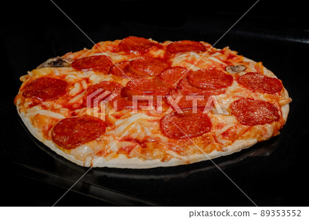 Baked pizza with pepperoni, cheese, sause on tray in electric oven Baked pizza with pepperoni, cheese, sause on tray in electric oven 89353552