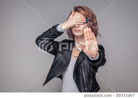 Stop, I dont want to see. Portrait of blocking girl with short hairstyle and makeup in casual style black leather jacket standing with stop gesture. indoor studio shot, isolated on grey background. Stop, I dont want to see. Portrait of blocking girl with short hairstyle and makeup in casual style black leather jacket standing with stop gesture. indoor studio shot, isolated on grey background. 89353867