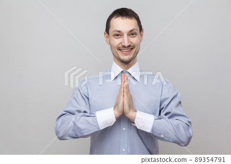 Portrait of happy handsome bristle businessman in classic light blue shirt standing with hands palm and looking at camera with toothy smile. indoor studio shot, isolated on grey background copyspace. Portrait of happy handsome bristle businessman in classic light blue shirt standing with hands palm and looking at camera with toothy smile. indoor studio shot, isolated on grey background copyspace. 89354791
