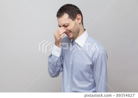 Profile side view portrait of sad lonely handsome bristle businessman in classic light blue shirt standing and crying. indoor studio shot, isolated on grey background copyspace. Profile side view portrait of sad lonely handsome bristle businessman in classic light blue shirt standing and crying. indoor studio shot, isolated on grey background copyspace. 89354827