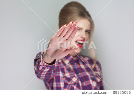 Stop it. angry girl in pink checkered shirt, collected updo hairstyle and makeup looking at camera with ban rejection or stop warning and screaming. indoor studio shot, isolated on gray background. 89355096