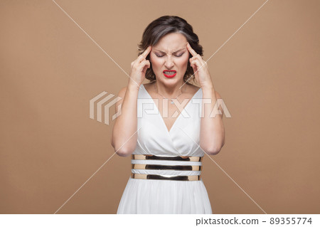 Woman unwell. Have headache and migraine. Emotion and feeling concept. Studio shot, indoor, isolated on light brown background Woman unwell. Have headache and migraine. Emotion and feeling concept. Studio shot, indoor, isolated on light brown background 89355774