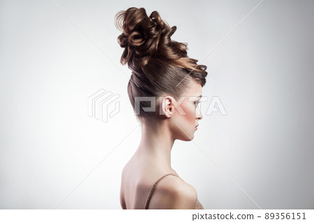 side view of attractive brunette woman with stylish hairdo and makeup posing on isolated grey background. indoor, studio shot on copy space. 89356151