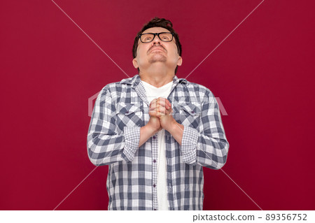 Oh god please help me. Portrait of hopeful sad worry middle aged man in casual checkered shirt and eyeglasses standing, praying and looking at up. indoor studio shot, isolated on dark red background. Oh god please help me. Portrait of hopeful sad worry middle aged man in casual checkered shirt and eyeglasses standing, praying and looking at up. indoor studio shot, isolated on dark red background. 89356752