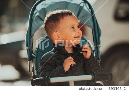 Sweet baby boy in a stroller bicycle outdoors. Little child in a pram. Infant kid in a pushchair. Spring walks with kids. 89356842