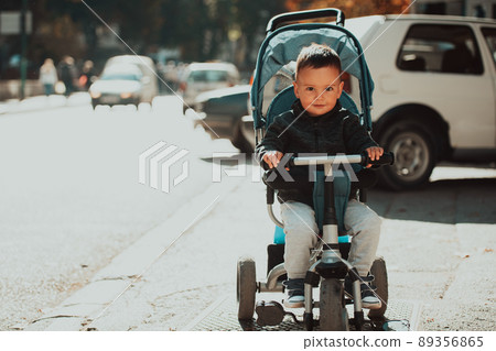 Sweet baby boy in a stroller bicycle outdoors. Little child in a pram. Infant kid in a pushchair. Spring walks with kids. Sweet baby boy in a stroller bicycle outdoors. Little child in a pram. Infant kid in a pushchair. Spring walks with kids. 89356865