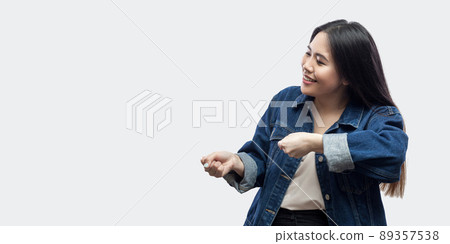 Profile side view portrait of funny beautiful brunette asian young woman in casual blue jacket with makeup standing and try to pulling showing gesture. studio shot, isolated on light grey background. 89357538