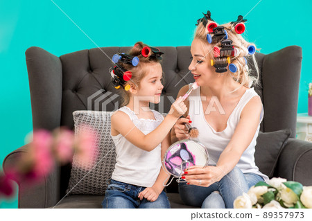 Portrait of cute little girl and her mom doing each other makeup Portrait of cute little girl and her mom doing each other makeup 89357973