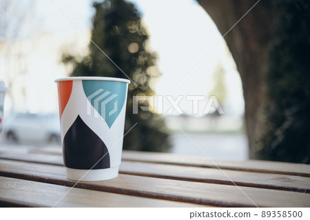 Paper cup with tea coffee drink on a wooden table against the background plant and a green wall. Zero West Concept. 89358500