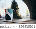Paper cup with tea coffee drink on a wooden table against the background plant and a green wall. Zero West Concept. 89358501