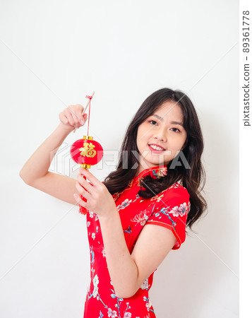 Portrait of young asian woman wearing traditional cheongsam qipao dress hold Chinese festival couplet to celebrate new year with word meaning good fortune on white background. Portrait of young asian woman wearing traditional cheongsam qipao dress hold Chinese festival couplet to celebrate new year with word meaning good fortune on white background. 89361778