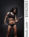 Female fitness model posing with dumbbells on black background 89362063