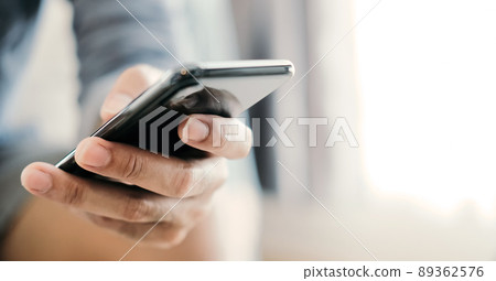 Close up man using smart phone at home 89362576