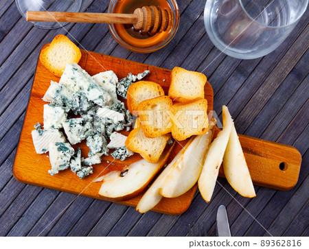 Soft roncari blue cheese with pear, croutons and honey on wooden board Soft roncari blue cheese with pear, croutons and honey on wooden board 89362816