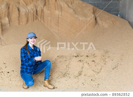 Woman farmer checking quality of soybean husk for livestock feeding 89362852