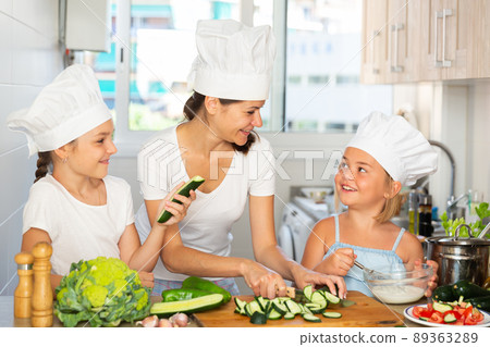 Young woman and two girls cooking together Young woman and two girls cooking together 89363289