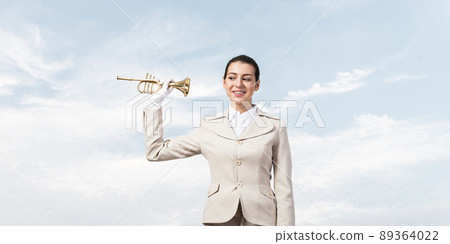 Beautiful woman holding trumpet brass near ear Beautiful woman holding trumpet brass near ear 89364022
