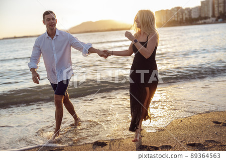 Carefree couple enjoying evening on beach together 89364563