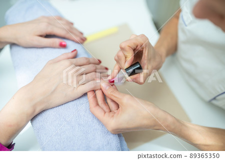 Applying shiny red nail polish Applying shiny red nail polish 89365350