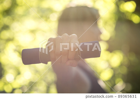 Side view of a woman exercising wth dumbbells in nature 89365631