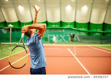 Instructor or coach teaching how to play tennis on a court indoor 89366357