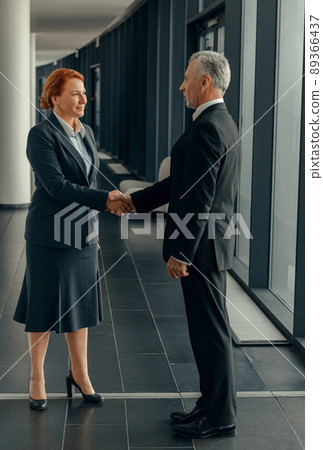 Full-length photo of business partners standing in hallway shaking hands 89366437