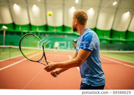 Instructor or coach teaching how to play tennis on a court indoor 89366629