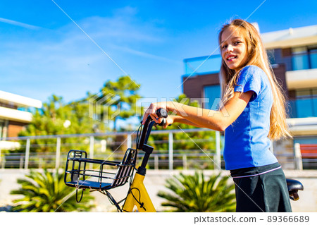 little girl having fun and smiling riding bicycle at the tropical beach 89366689