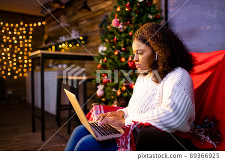 afro woman shopping online on laptop in cozy christmas interior.Preparing to xmas, bying on winter sales 89366925