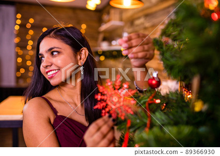 indian woman decorating the christmas tree alone self-isolation quarantine corona virus covid outbreak stay at home 89366930