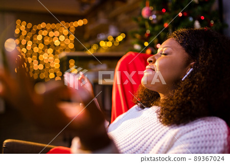Serene young woman closed eyes relaxing leaned on couch modern wireless headphones in an ear pods Serene young woman closed eyes relaxing leaned on couch modern wireless headphones in an ear pods 89367024