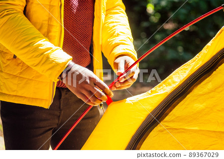 african american in yellow jacker putting on a tent in forest african american in yellow jacker putting on a tent in forest 89367029