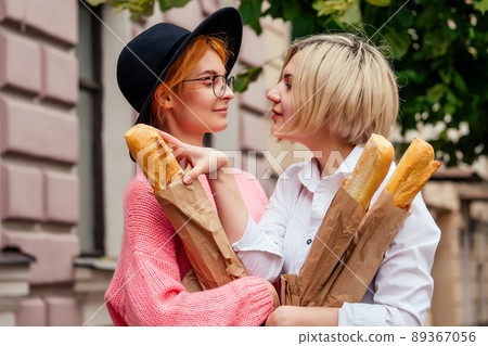 redhaired young ginger woman feeling love to her blonde girlfriend in Europe streets 89367056