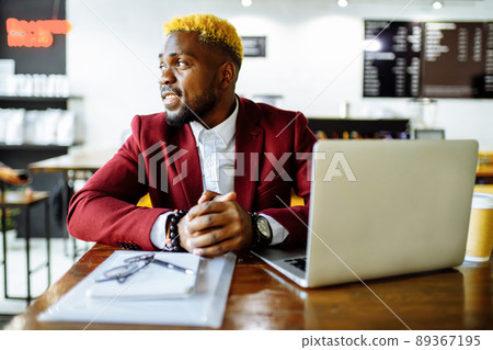 african american person sitting at office typing message note on phone near laptop 89367195