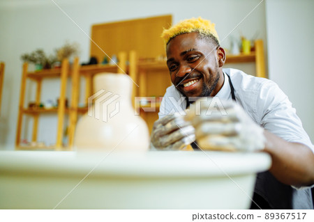 Portrait of positive latin hispanic brazilian man making ceramic pot on pottery wheel 89367517