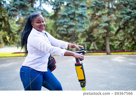 mixed race woman riding an electric scooter in the summer on the street mixed race woman riding an electric scooter in the summer on the street 89367566