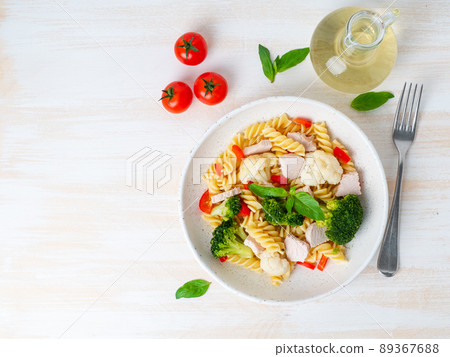 Pasta fusilli with vegetables, turkey meat on white wooden table, low-calorie diet, low-fat food, top view, copy space 89367688