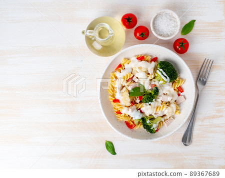 Pasta fusilli with vegetables, meat, white sauce on white wooden table, low-calorie diet, low-fat food, top view, copy space 89367689