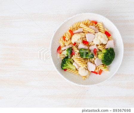 Pasta fusilli with vegetables, boiled steamed meat, white sauce on white wooden table 89367698