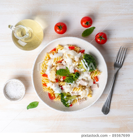 Pasta fusilli with vegetables, boiled steamed meat, white sauce on white wooden table Pasta fusilli with vegetables, boiled steamed meat, white sauce on white wooden table 89367699