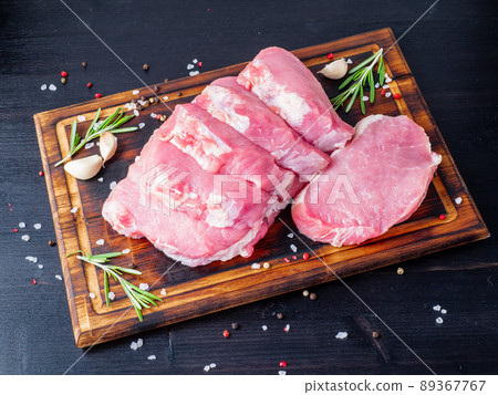 Pork steak, raw carbonate fillet on dark background, meat with rosemary, seasonings, side view Pork steak, raw carbonate fillet on dark background, meat with rosemary, seasonings, side view 89367767